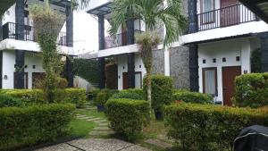 a courtyard of a building with a palm tree and bushes at Beruk Angis Guest House & Kost in Palangkaraya