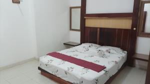 a bedroom with a bed with a wooden headboard at Beruk Angis Guest House & Kost in Palangkaraya