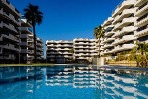 a swimming pool in front of two apartment buildings at Sea Arenales del Sol in Arenales del Sol