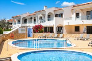a villa with a swimming pool in front of a building at Carvoeiro -Spacious 2 bedroom appartment with pool - Monte Dourado in Carvoeiro