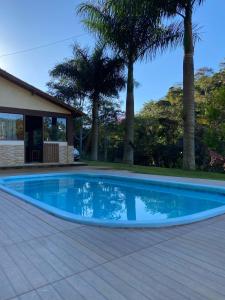 a blue swimming pool with palm trees in the background at Recanto do Ziu in Santa Teresa