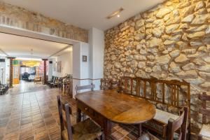 a dining room with a stone wall and a wooden table at El Sueño De Lucrecia in Villarrubia de Santiago