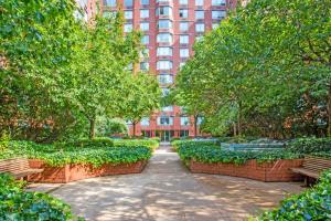 ein Park mit Bänken und Bäumen und ein hohes Gebäude in der Unterkunft UWS 2BR w Doorman Gym Parking nr Central Park NYC-596 in New York