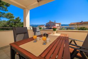 a wooden table with two glasses of orange juice on a balcony at Apartment Iva in Šilo