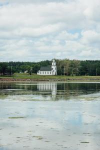 a white building on the shore of a body of water at Greenwich View Cottages (Unit #3) in Saint Peters