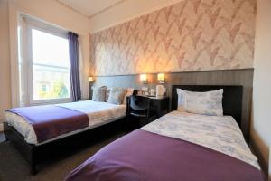 a hotel room with two beds and a window at Edinburgh Holiday Guest House in Edinburgh