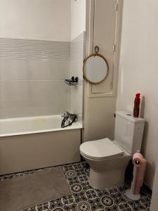 ein Badezimmer mit einem WC, einer Badewanne und einem Spiegel in der Unterkunft Apartment in Cergy Prefecture in Cergy