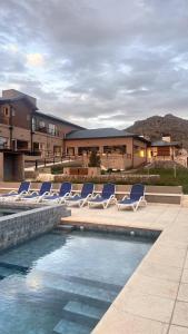 a group of lounge chairs sitting next to a swimming pool at Pie de Piedra Hotel Boutique in Sierra de la Ventana