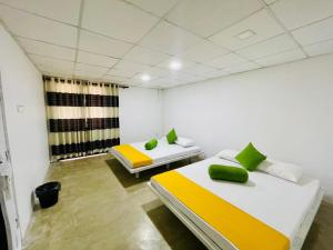 a room with two beds with green and yellow pillows at Relish Tourist Hostel in Nikawatawana