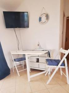 a white desk with two chairs and a television on a wall at Sun and Sea Apartmani Vir Mali in Vir +2 photos