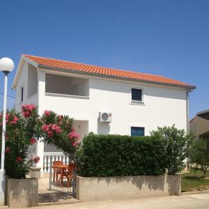a white house with a table and a fence and flowers at Sun and Sea Apartmani Vir Mali in Vir
