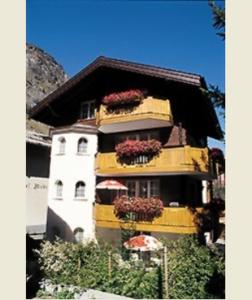 a yellow and white building with flower boxes on it at Alcamar in Zermatt