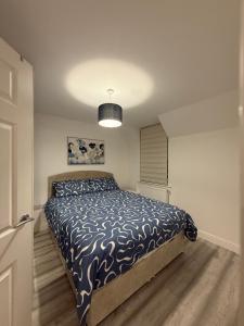 a bedroom with a bed with a blue and white comforter at Blue Oyster Cottages in Poole