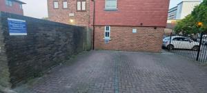 a brick wall next to a building with a sign on it at Blue Oyster Cottages in Poole