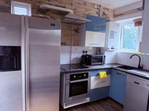 a kitchen with stainless steel appliances and blue cabinets at Spacious Room in Manchester in Middleton