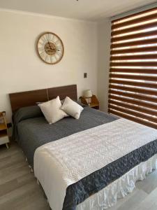 a bedroom with a large bed with a clock on the wall at Acogedor Dpto, Playa y Piscinas in La Serena +18 photos
