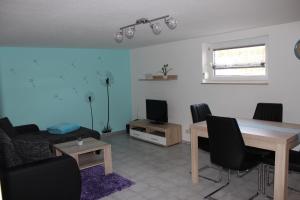 ein Wohnzimmer mit einem Tisch, Stühlen und einem TV in der Unterkunft Ferienwohnung NeLe in Kappel-Grafenhausen