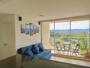 un salon avec un canapé bleu et une grande fenêtre dans l'établissement Apartamento Vacacional en Ricaurte Cundinamarca, Entre Melgar y Girardot, à Ricaurte