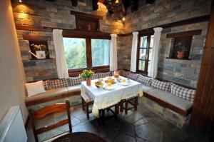 a dining room with a table and chairs and windows at Amalthia Traditional Guesthouse in Tsagarada