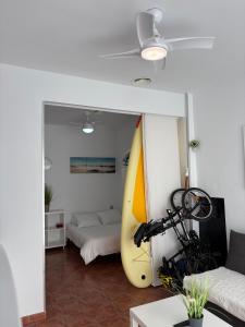 a living room with a surfboard and a bed at La Manga km 0, pisos estudios - planta baja - 100m de la playa - studio flats - ground floor - 100m from the beach, cada con bicis & tabla SUP, piscina & pádel & tenis & más - each with bikes & SUP board, pool & paddle & tennis & more in La Manga del Mar Menor
