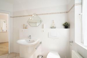 a white bathroom with a sink and a toilet at Appartement-Konsulweg-KON-375 in Scharbeutz +30 photos