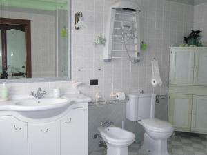 a bathroom with a sink and a toilet and a mirror at Il Portico in Uras
