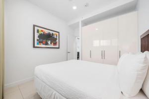a white bedroom with a white bed and a picture on the wall at Arubas Life 201 in Noord +51 photos