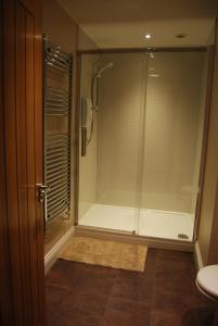 a shower with a glass door in a bathroom at Malvern Stables in Great Malvern