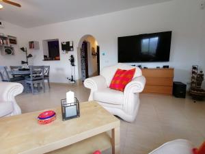 a living room with two white chairs and a flat screen tv at Luxury Pool Villa in Arenas - Andalusia in Los Valverde