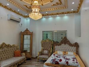 a bedroom with a bed and a couch and a chandelier at Rajmahal in Sylhet