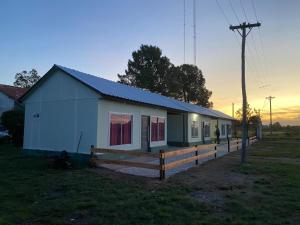 una pequeña casa blanca con una valla en un campo en Cabañas Emilia, en La Adela 5 fotos más