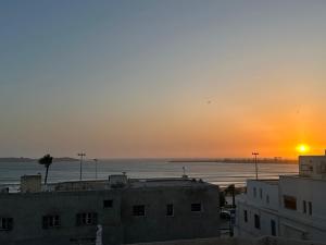 a sunset over the ocean from a city with buildings at Sea View Private Terrace - Fibre Wi-Fi & Netflix in Essaouira