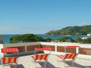 un patio con sillas y mesas rojas y el océano en Hotel Aurora, en Scauri