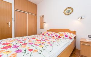 ein Schlafzimmer mit einem Bett mit geblümter Tagesdecke in der Unterkunft Apartments Lucija in Baška + 24 Fotos