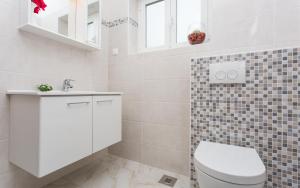 ein weißes Badezimmer mit Toilette und Waschbecken in der Unterkunft Apartments Lucija in Baška