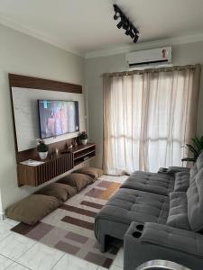 a living room with a couch and a flat screen tv at Edifício Gorja in Praia Grande