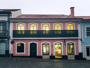 英雄港Aurora Hostel的粉红色的建筑,在街上设有阳台