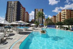 a large swimming pool with chairs and umbrellas at Apartamentos Eldorado Thermas Park in Caldas Novas