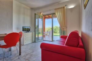 a living room with a red couch and a table at Country House Vignola Mare in Aglientu