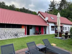 a house with a red roof with chairs and an umbrella at Family-friendly apartments with swimming pool Lic, Gorski kotar - 23685 in Fužine