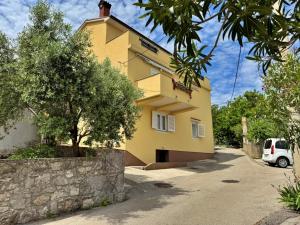 żółty dom z samochodem zaparkowanym przed nim w obiekcie Apartments by the sea Silo, Krk - 18715 w mieście Šilo +10 zdjęć