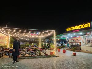 a man standing in front of a store with lights at Islamabad Dream Palms Guest House Hotel in Islamabad