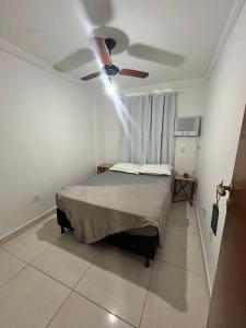 Un dormitorio con una cama y un ventilador de techo. en Apartamento aconchegante no Recreio, en Río de Janeiro
