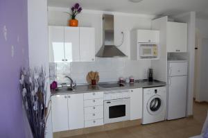 cocina con armarios blancos, fregadero y lavavajillas en Residencial Jandía Marina, en Morro del Jable