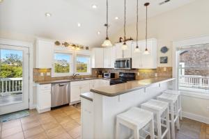 una cocina con armarios blancos y taburetes blancos en 6095 - Blessed, en Nags Head