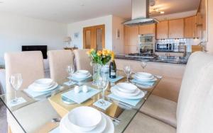a dining room and kitchen with a table with plates and glasses at Coastal Haven- stunning home in Crail in Crail