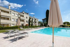 托斯科拉诺-马德尔诺Corte Fasanella appartamento Lillà的建筑物旁边有带椅子和遮阳伞的游泳池