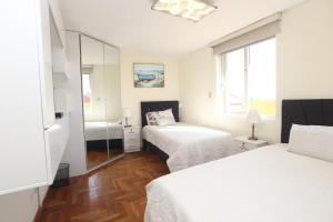 a white bedroom with two beds and a mirror at Brand new apartment 4 blocks from Plaza Armas Arequipa in Arequipa