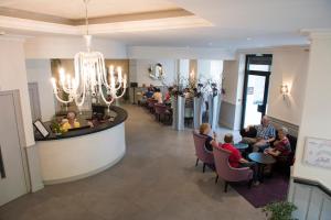 a lobby of a restaurant with people sitting in chairs at Hôtel Esplanade Eden in Lourdes