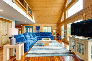 a living room with a blue couch and a tv at Mtn-View Deck Scenic Conway Log Cabin! in Conway